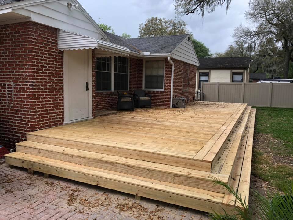 Multi-tiered wood deck with seating at a brick home in Jacksonville, FL