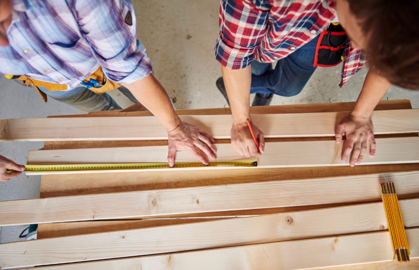 Measuring and marking wood planks for custom deck building.