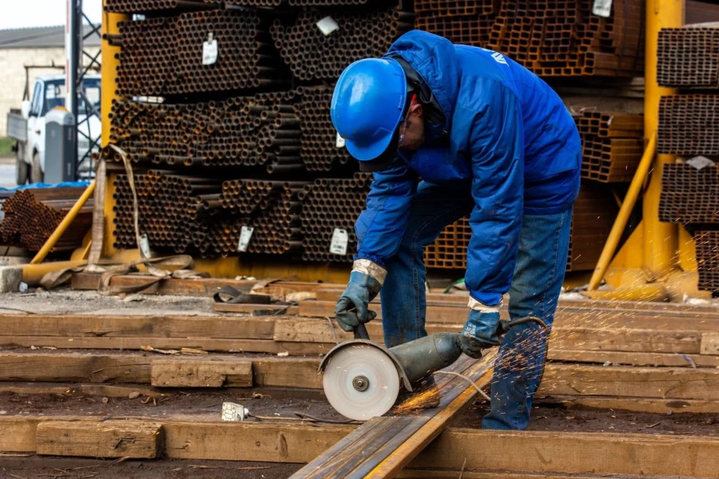 Worker cutting metal with a grinder in a warehouse.
