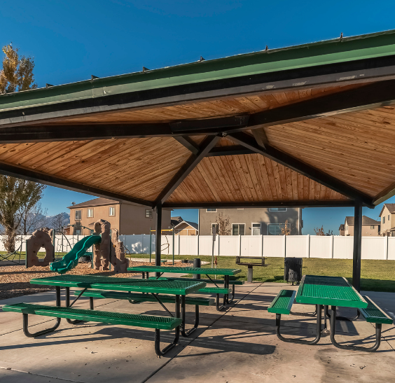 Park pavilion with picnic tables and playground in the background