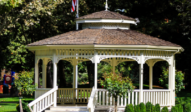 Wooden gazebo with decorative trim in a landscaped garden