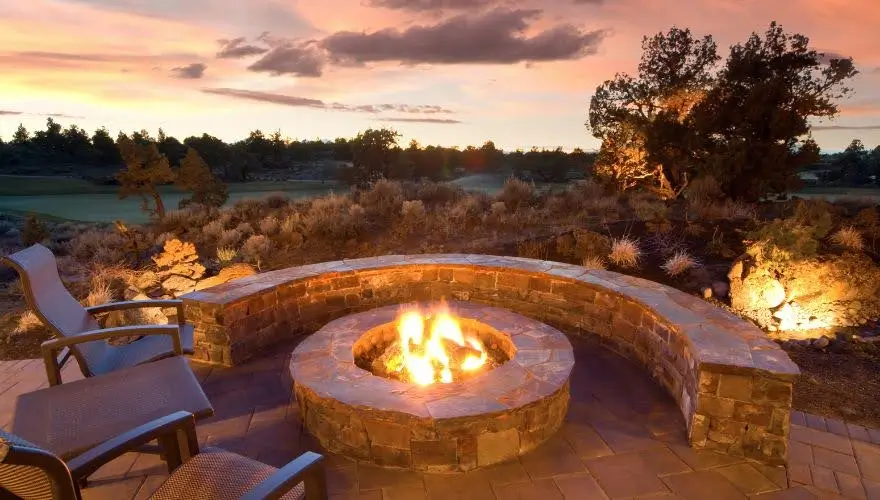 Fire pit surrounded by seating, sunset sky, outdoor living.