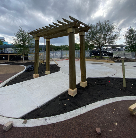 Wooden pergola structure in a landscaped outdoor area.