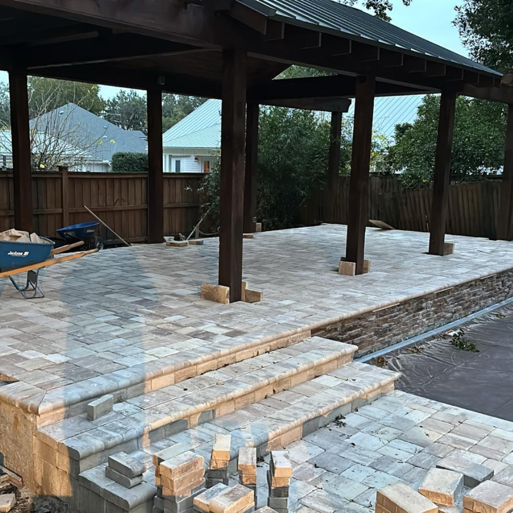 Paver patio installation with steps and wooden pergola structure.
