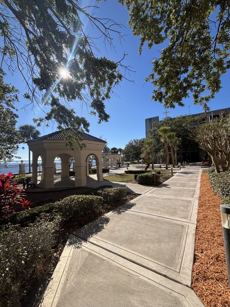 Scenic outdoor walkway with gazebo and landscaped gardens.