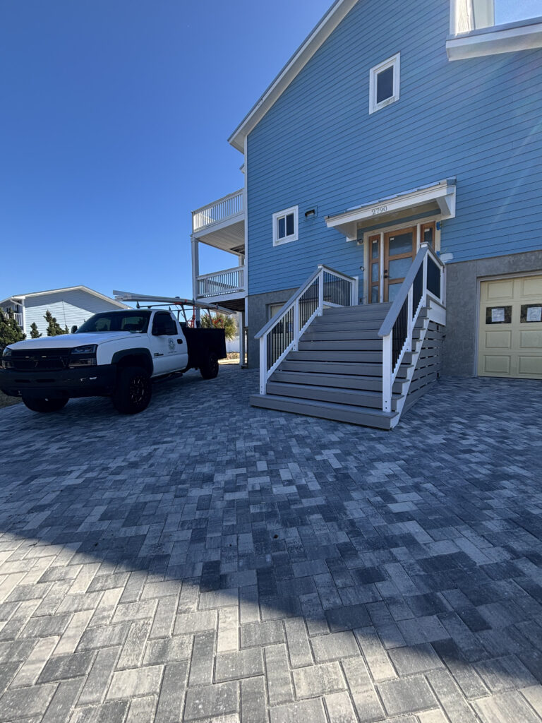 Paver driveway with steps to blue house.
